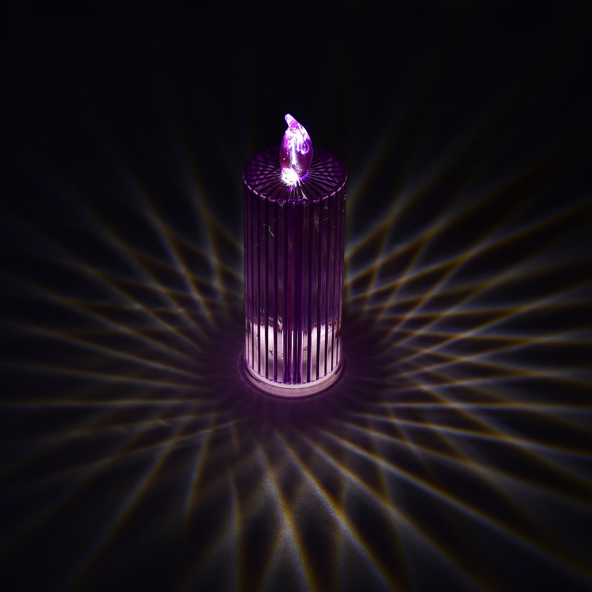 A single purple LED crystal candle casting intricate swirling light patterns on a dark surface.