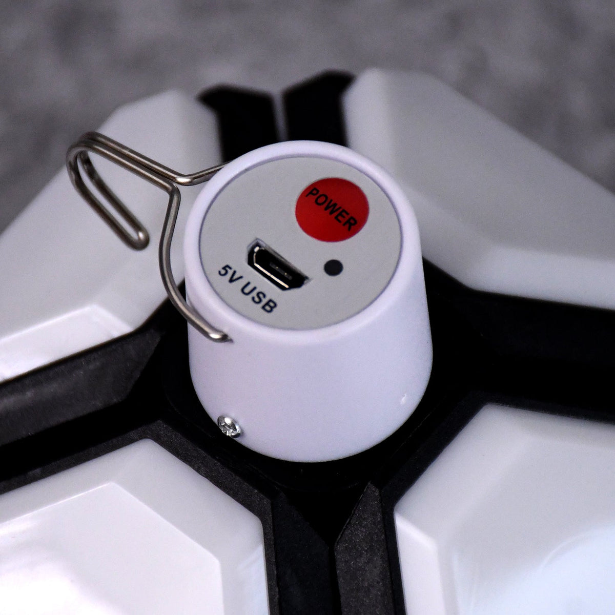 Close-up of the white top of the lantern showing a red power button, a 5V USB port, and a metal hook.