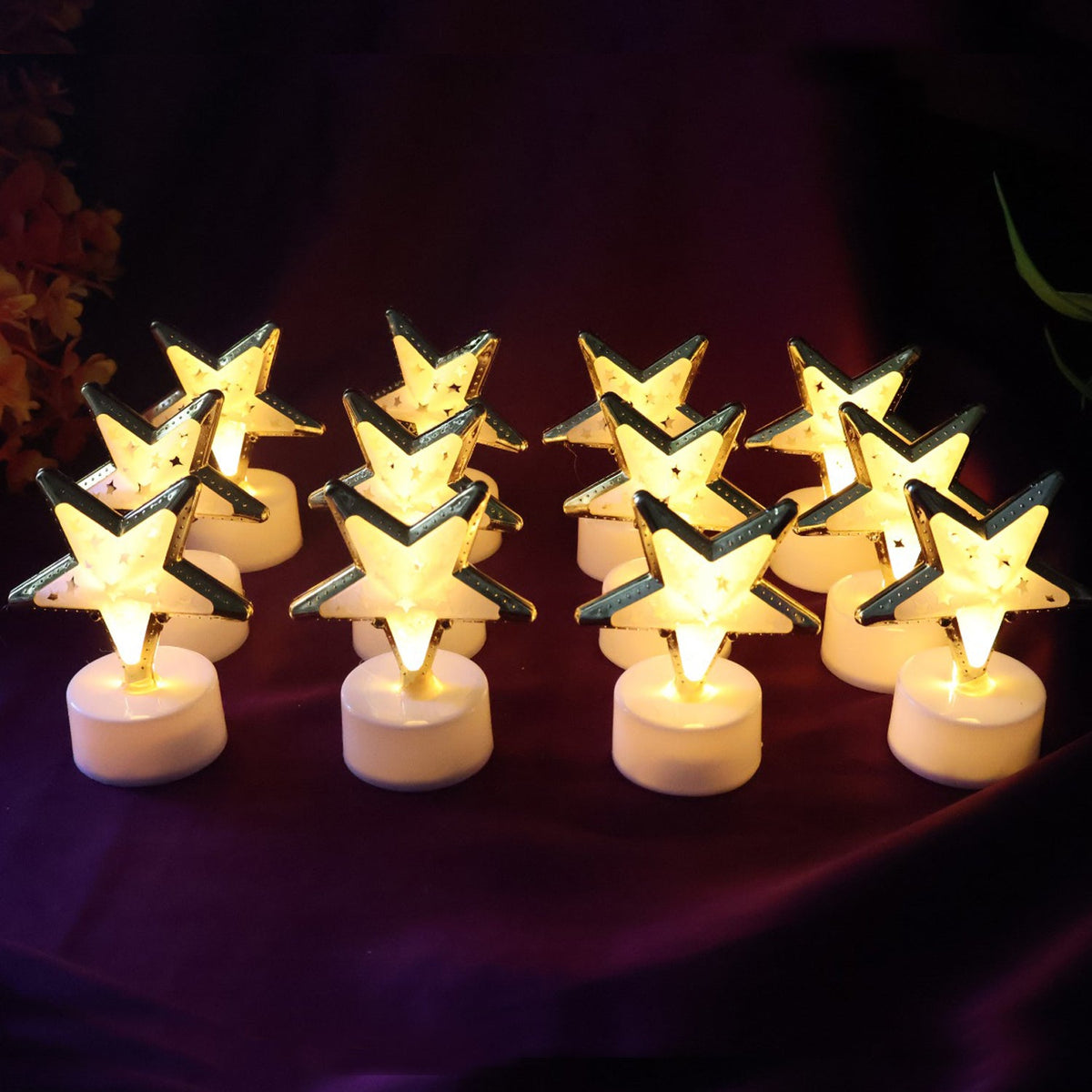 Twelve glowing star-shaped LED candles with gold frames and white bases arranged on a rich purple fabric.