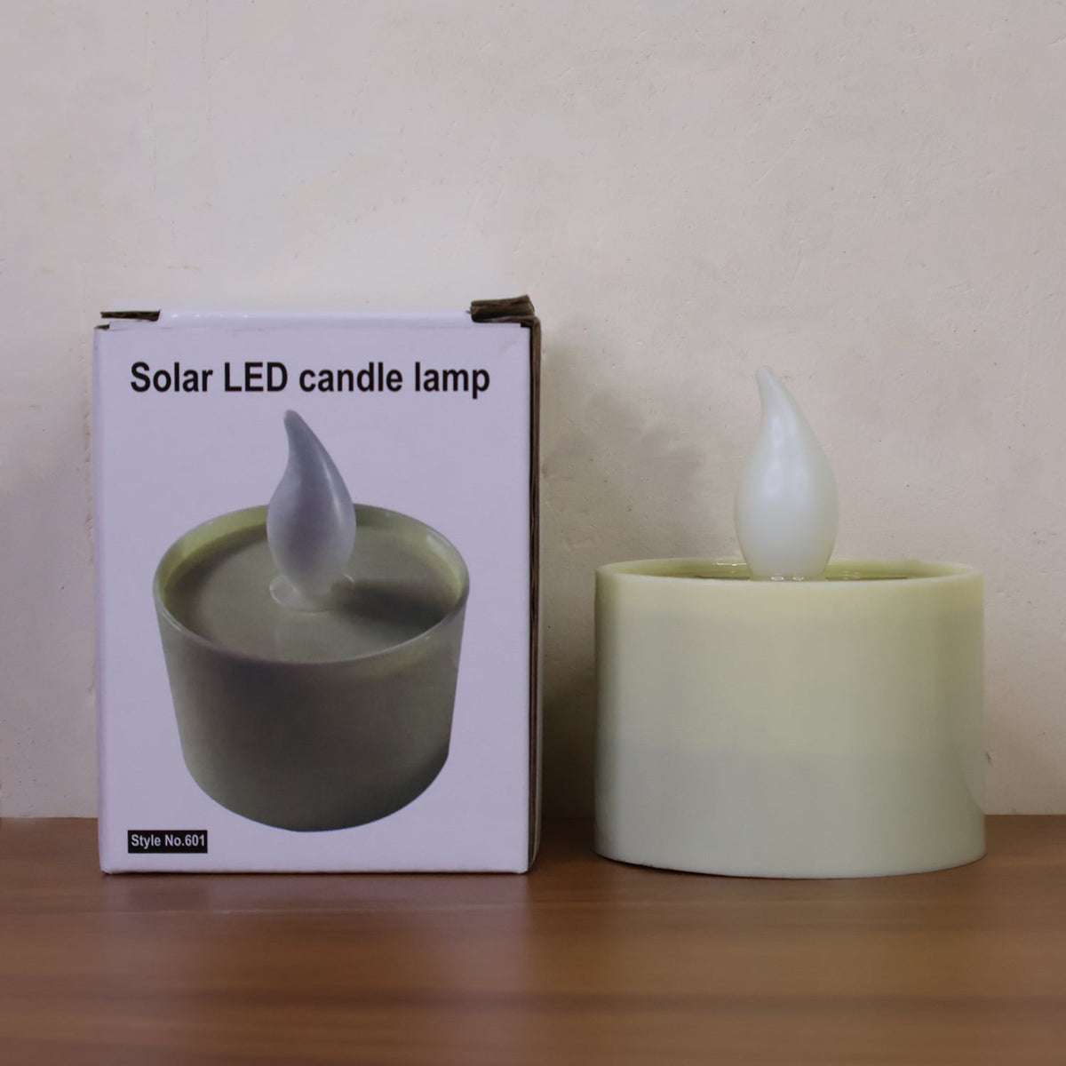 An unlit solar LED candle lamp next to its white product box, which displays a picture of the lamp.