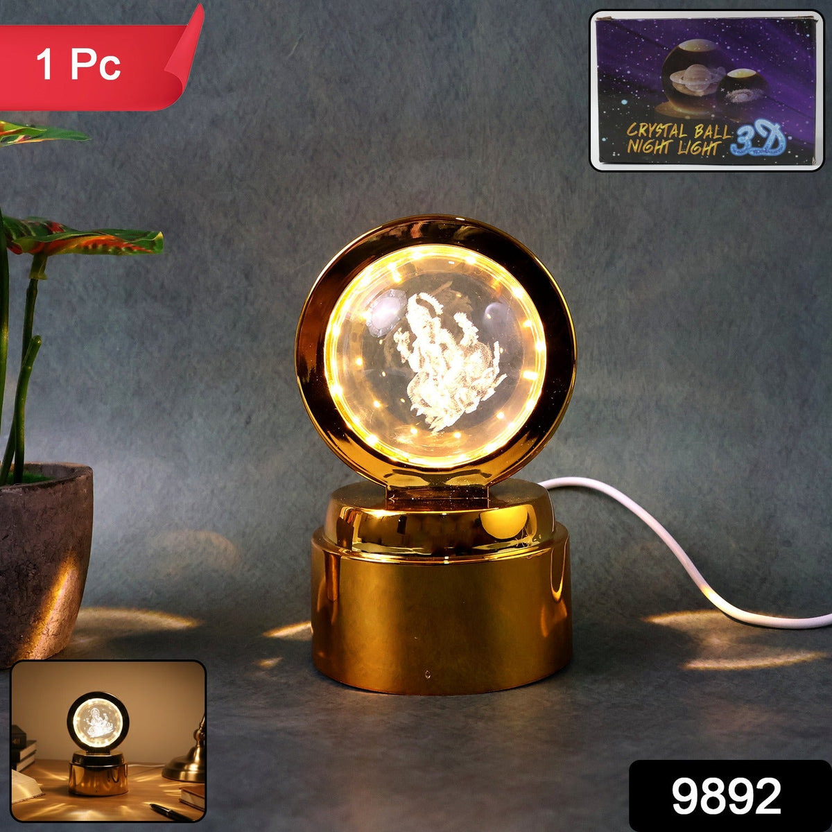 A golden LED night light with a glowing 3D Ganpati crystal ball, next to a potted plant, with a '1 Pc' label.