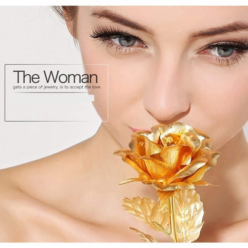 A woman's face is shown close-up, with a gold-plated rose held near her nose.