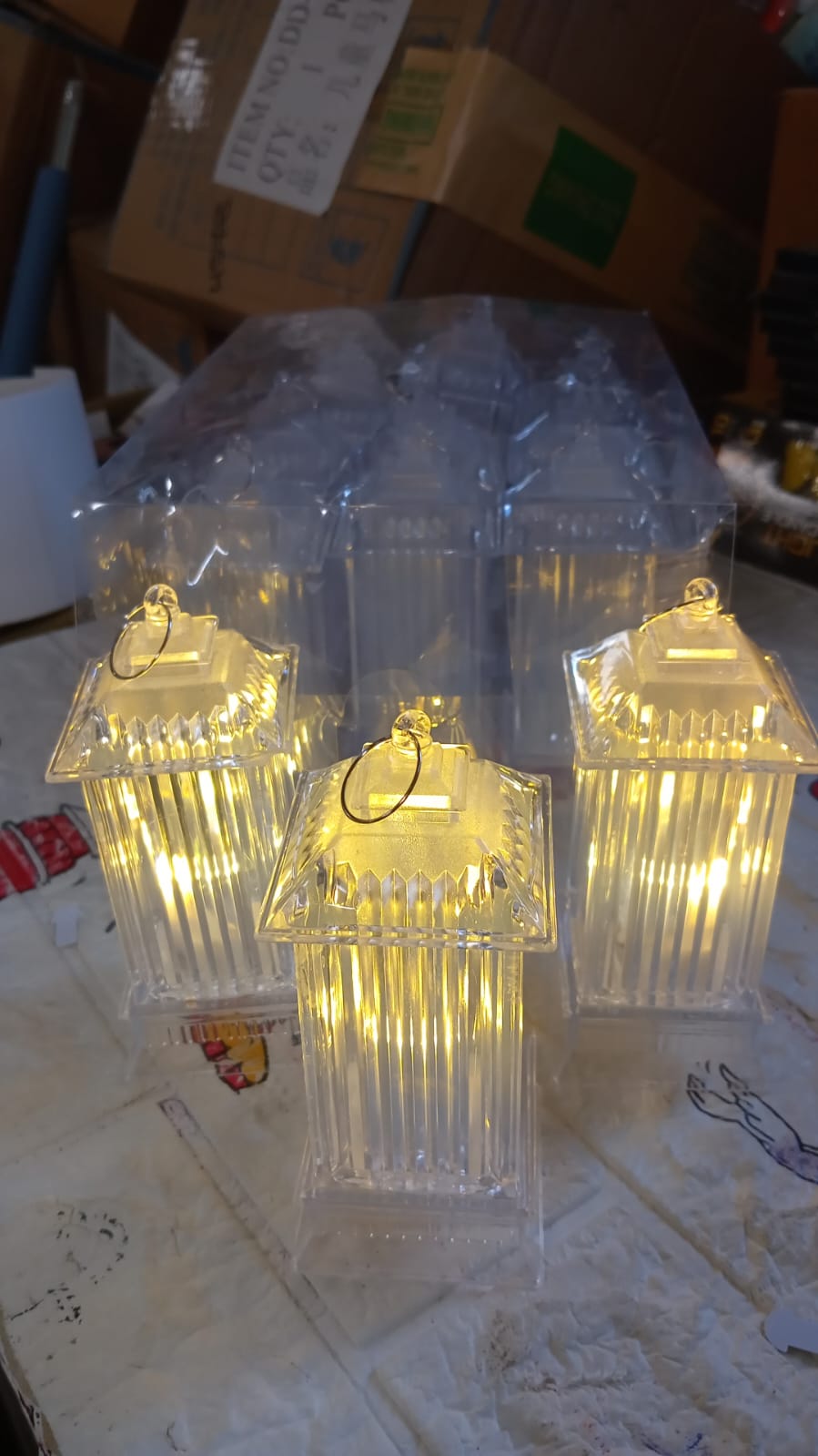 Three glowing LED crystal lantern lamps are displayed with their clear packaging in a casual indoor setting.