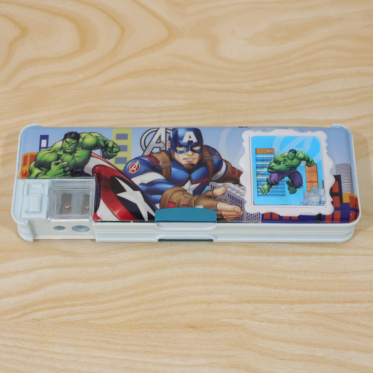 A light blue pencil box featuring Avengers characters and a built-in sharpener, resting on a wooden surface.