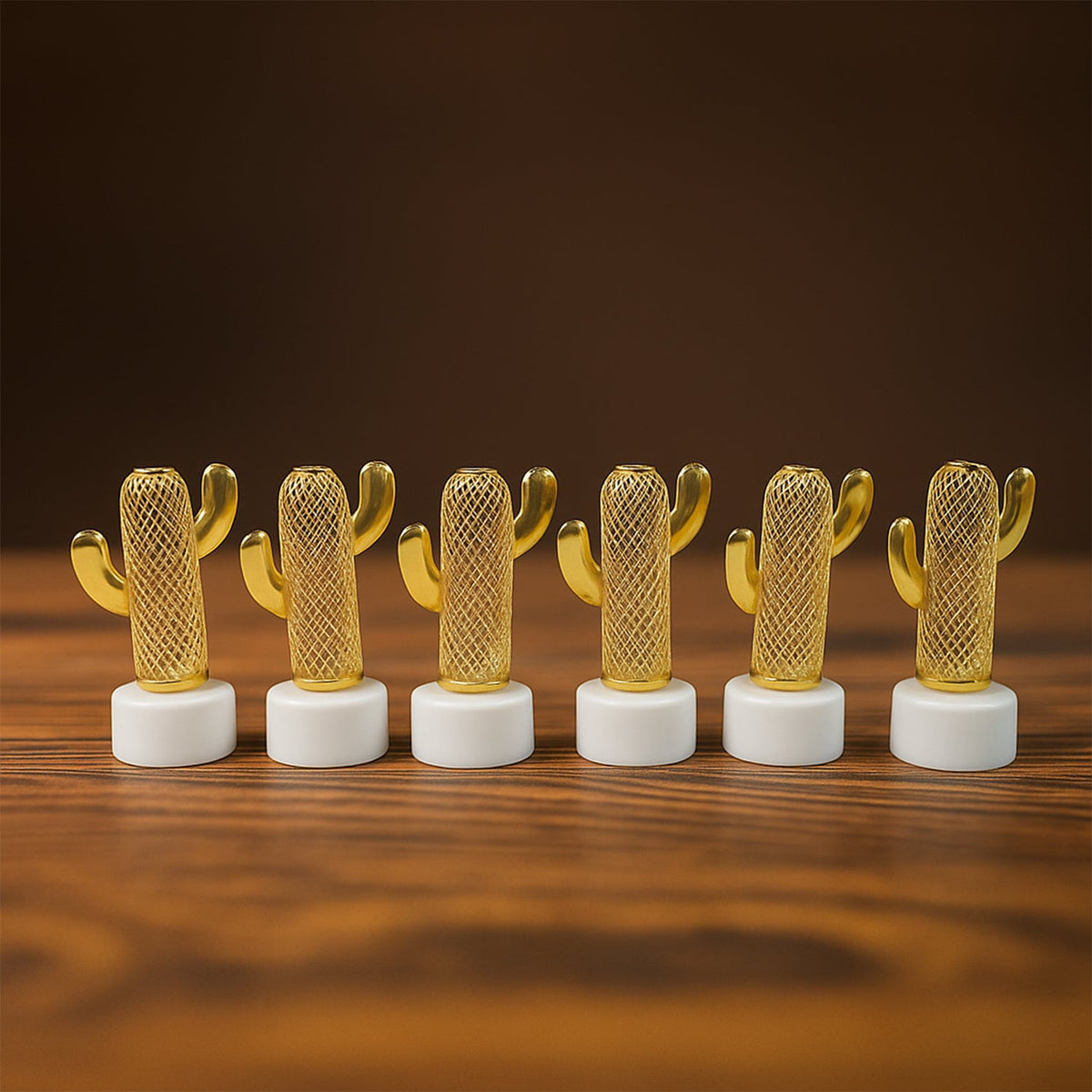 Six golden cactus-shaped LED lights with white bases, unlit, arranged in a line on a wooden surface.