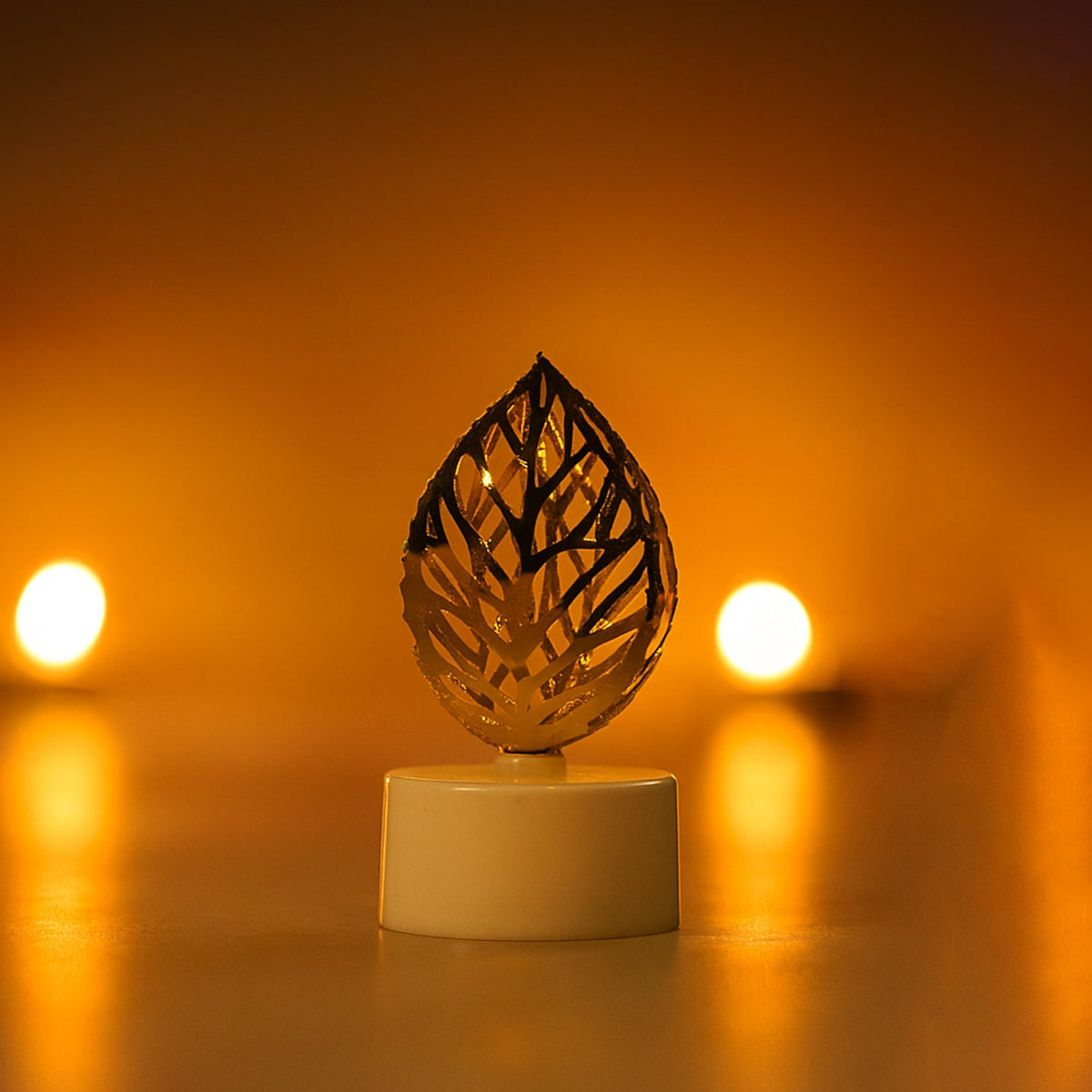 A single golden leaf LED candle with a white base glowing brightly against a blurred warm background.
