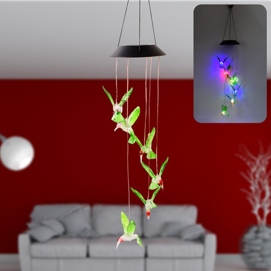 Solar hummingbird wind chime illuminated in a garden