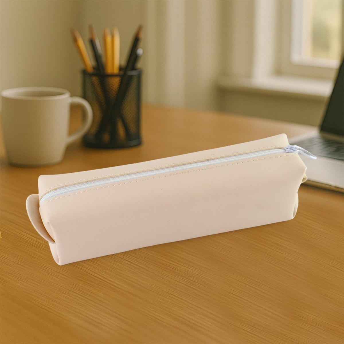 Beige pencil case on a wooden desk with a coffee mug and pen holder in the blurred background.